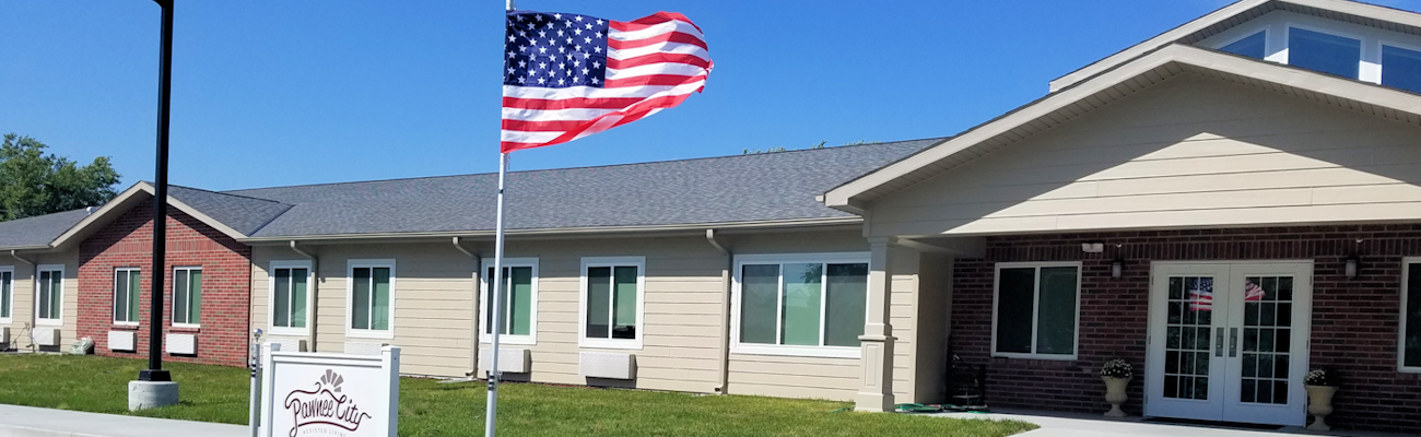 Entrance to Pawnee City Assisted Living with flag flying high.